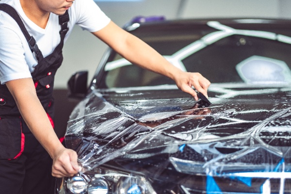 Mężczyzna nakleja folię ochronna na auto