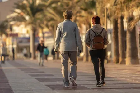 Spacerująca para osób w starszym wieku na tle palm.